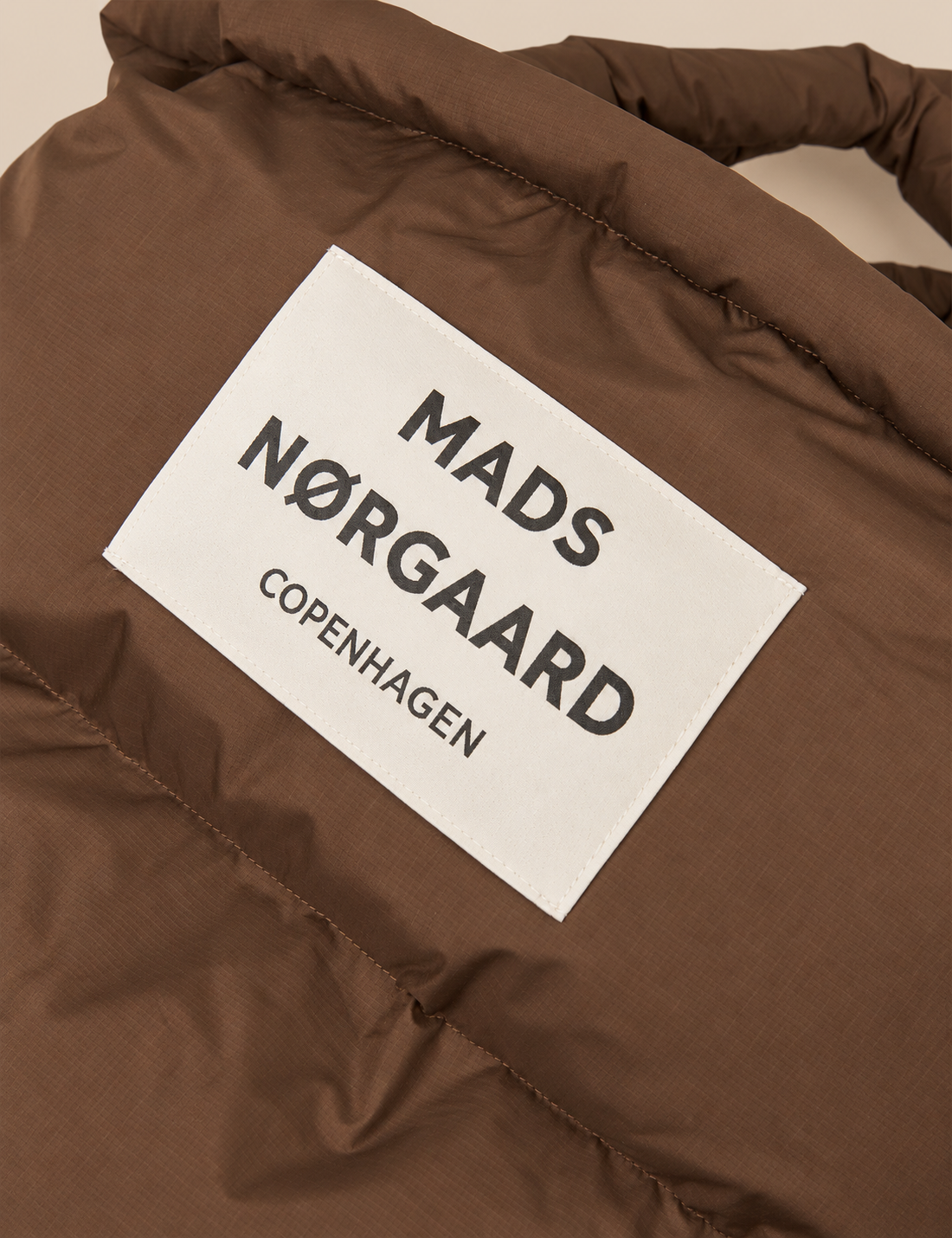 Close up of Light Ripstop Pillow Bag in cocoa brown, an oversized lightweight puffer tote bag with dual carrying handles and recycled polyester fabric.