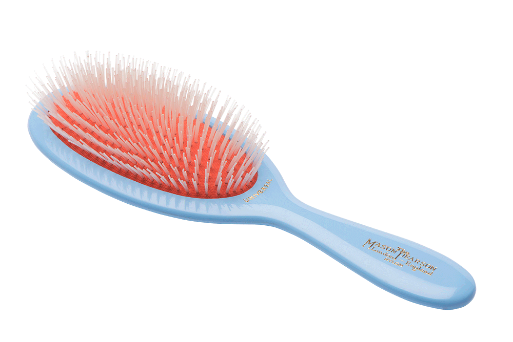 A MASON PEARSON Universal Brush NU2 with a blue handle and orange bristles, lying against a white background.
